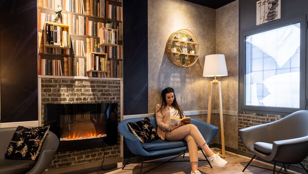 A cozy reading area with a fireplace, bookshelves, and comfortable seating.