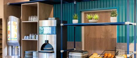 A self-service breakfast station with a coffee machine, toaster, and various food items.