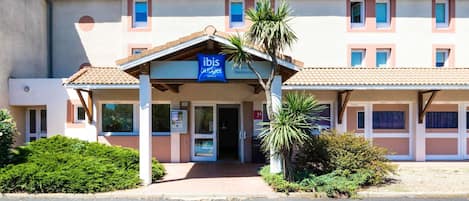 Ett hotell i två våningar med en skylt där det står ”ibis budget hotels”.