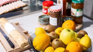 Una encimera de cocina con una cesta de frutas, una hogaza de pan y frascos de condimentos.