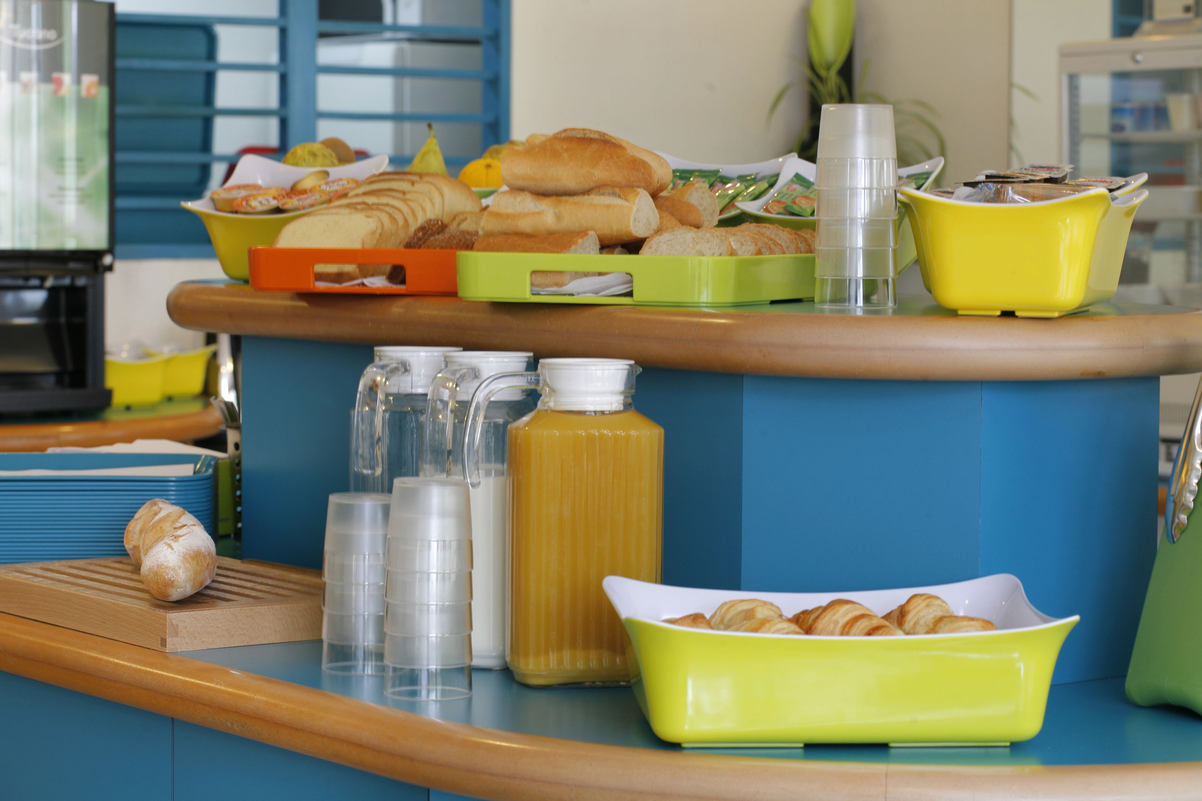 A breakfast buffet with various pastries, a juice dispenser, and a coffee station.