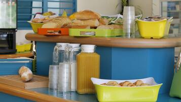 A breakfast buffet with various pastries, a juice dispenser, and a coffee station.