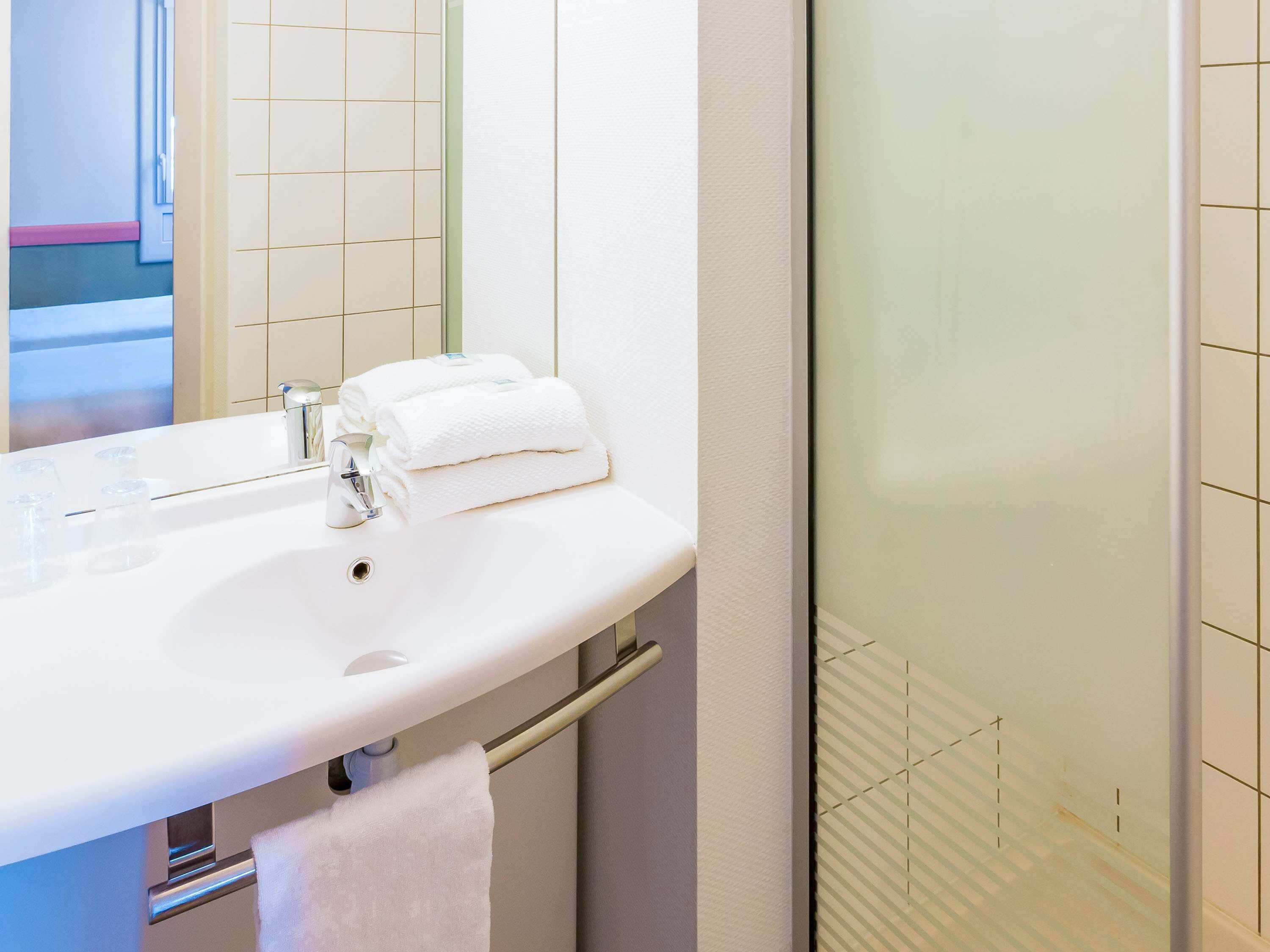 Een badkamer met een witte wastafel, een spiegel en een handdoekhouder.