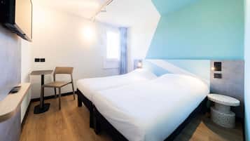 Una habitación de hotel moderna con una cama, un escritorio, una silla y un televisor.