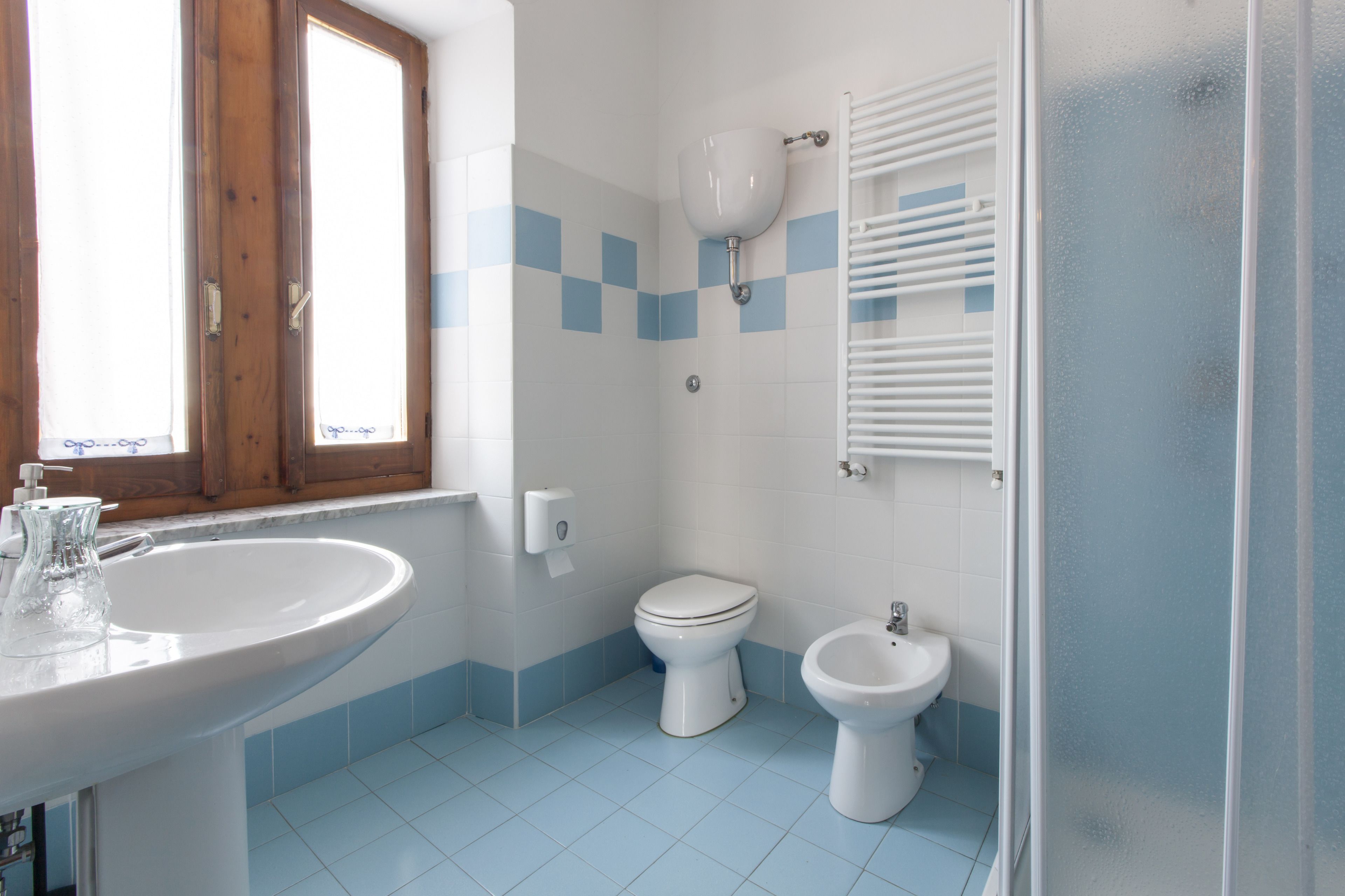 Een badkamer met een wastafel, toilet, bidet en een raam.