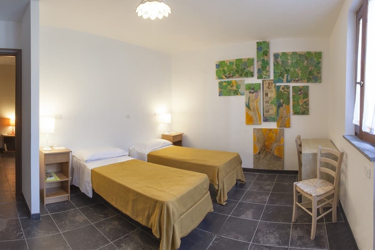 Ett hotellrum med två sängar, ett litet bord, en stol och konstverk på väggen.