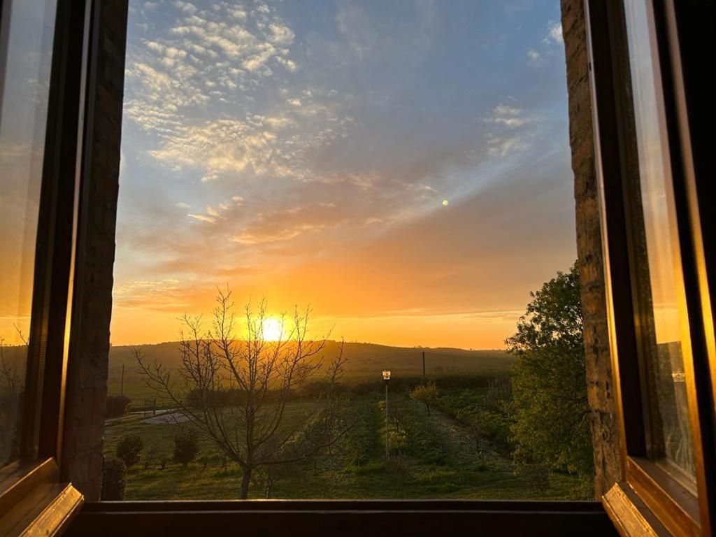 Vista desde una ventana de un atardecer sobre un paisaje con una señal de tráfico a lo lejos.