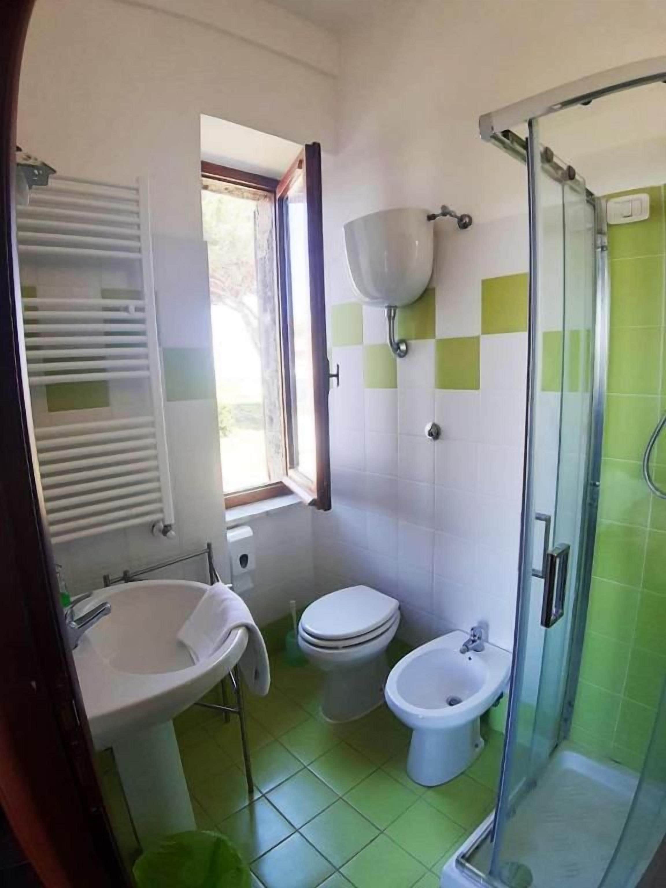 A bathroom with a sink, two toilets, a shower, and a window.