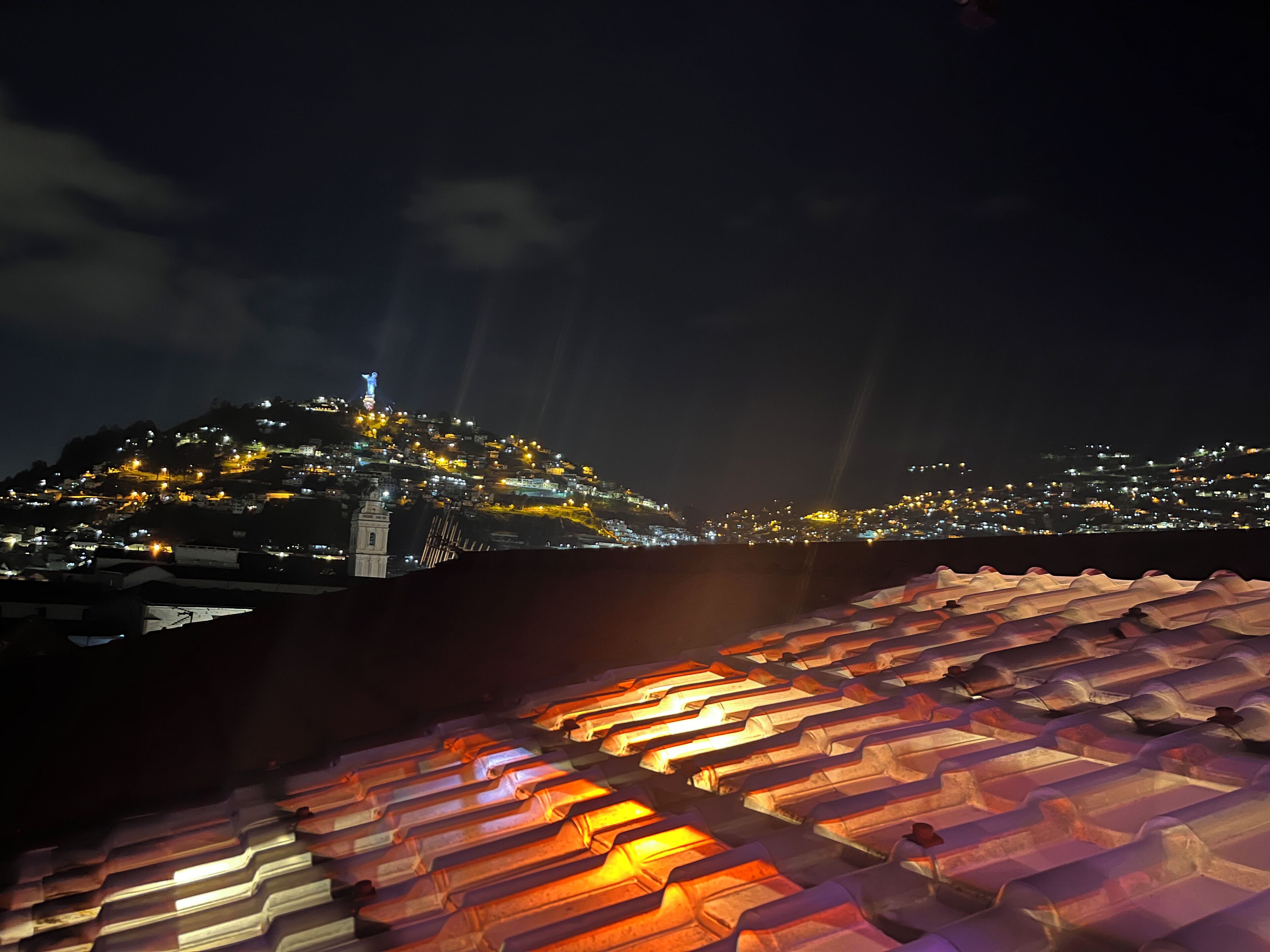 Un paisaje urbano nocturno con edificios iluminados y una prominente aguja de iglesia.