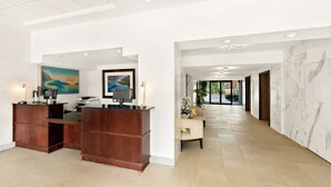 A spacious lobby with a reception desk, a seating area, and a view into the hallway. - Sonesta Essential Atlantic City West (Egg Harbor Township)