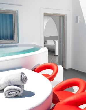 A modern hotel room with a private hot tub, a bed, and a view of the sea. - Drops villas (Santorini)