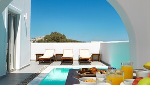 A poolside area with lounge chairs, a dining table with breakfast, and a clear view of the sky and distant landscape. - Drops villas (Santorini)