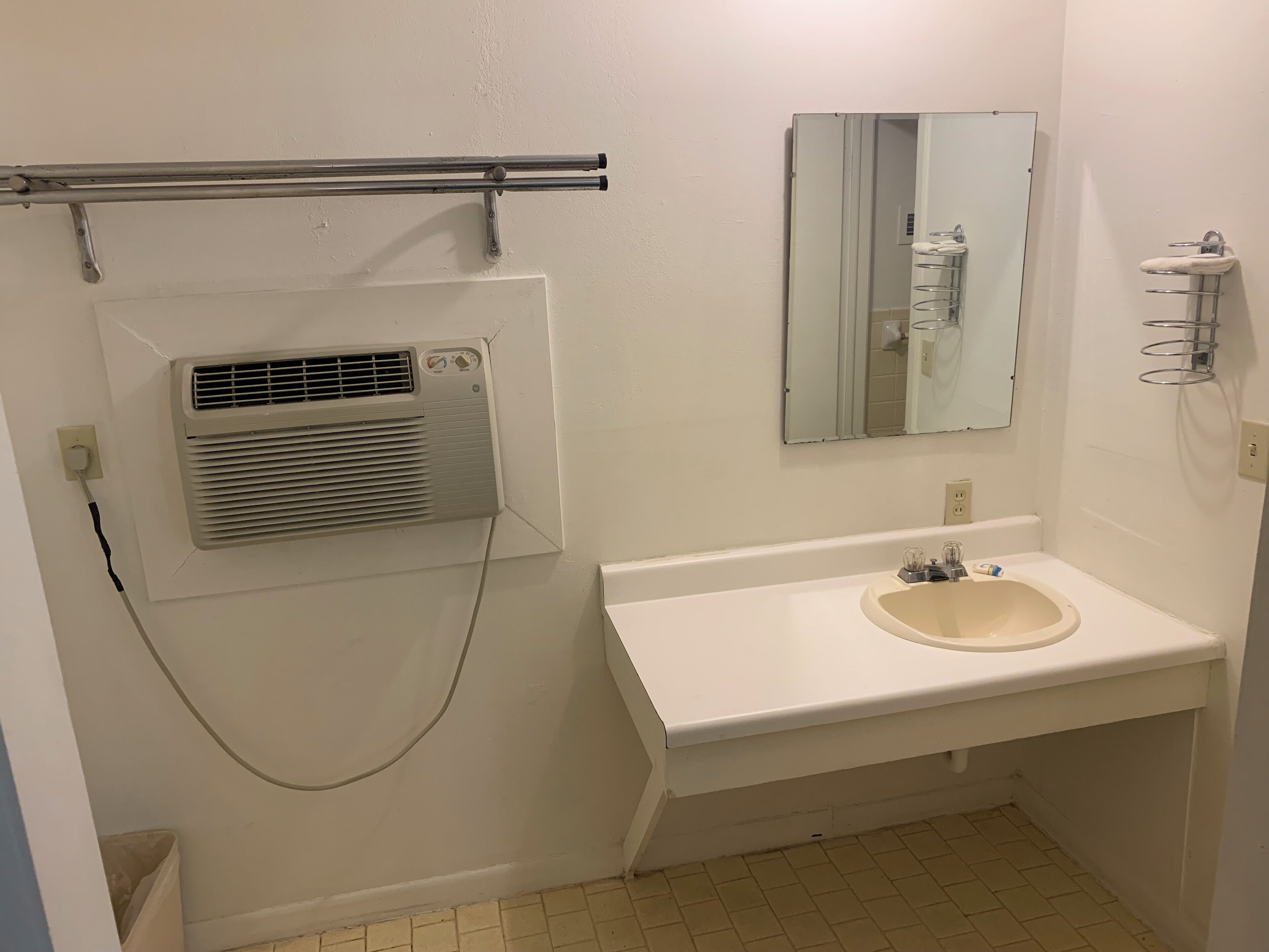 Baño con lavamanos, espejo y extractor de aire.