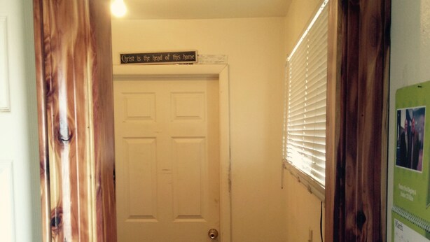 A wooden-framed entryway with a sign above a white door that reads "Christ is the head of this home." - Sawmill Lodges Motel (Hennessey)