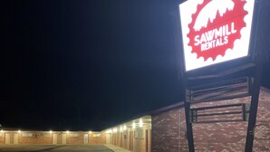 A building with a sign for 'Sawmill Rentals' at night. - Sawmill Lodges Motel (Hennessey)