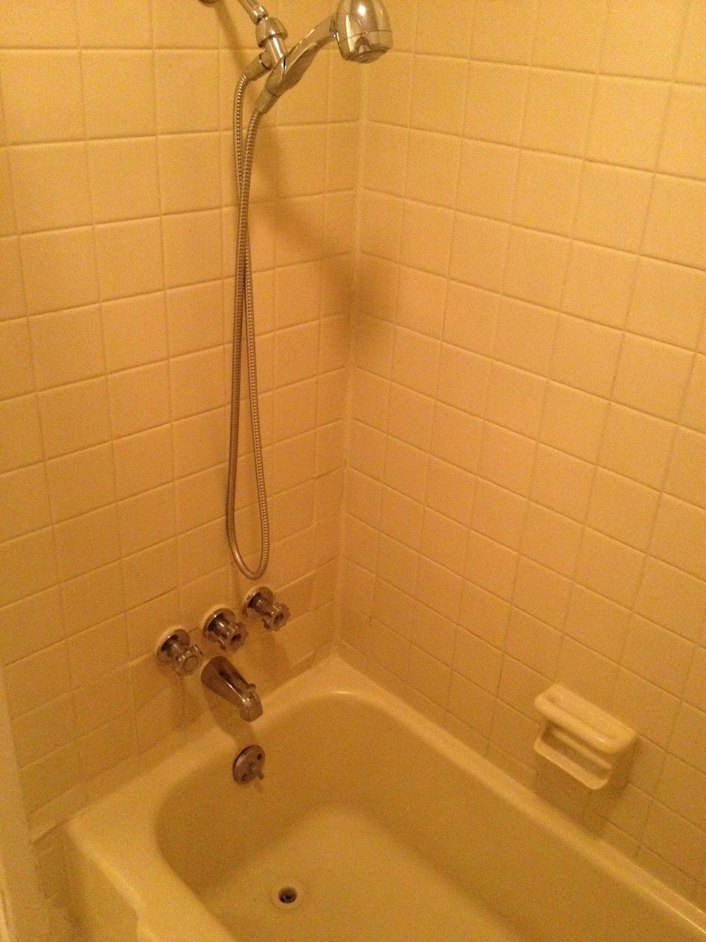 A bathroom with a bathtub, a showerhead, and a toilet.