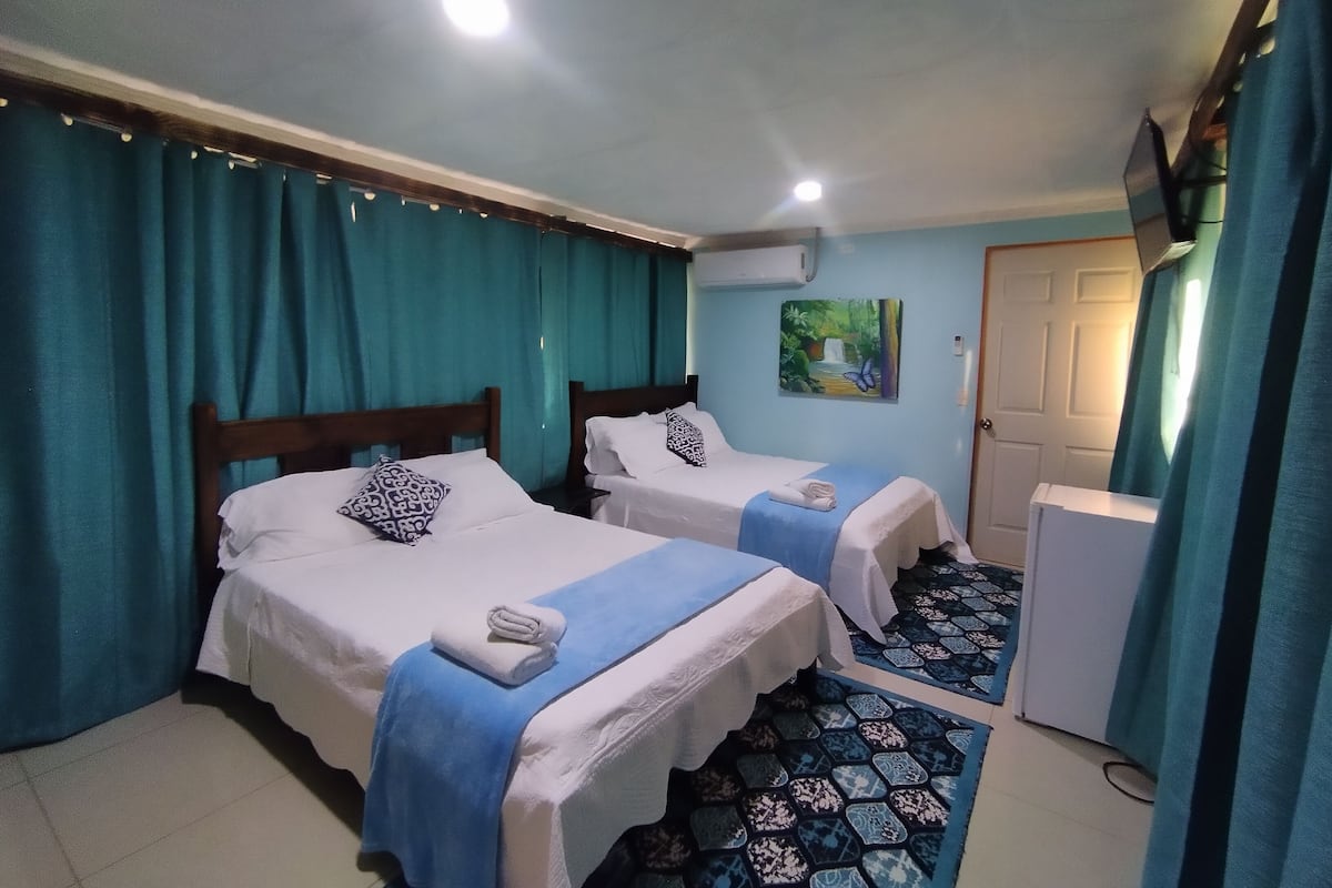 Une chambre d’hôtel avec deux lits, un réfrigérateur et un tableau au mur.