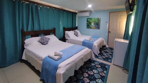 A hotel room with two beds, a refrigerator, and a painting on the wall.