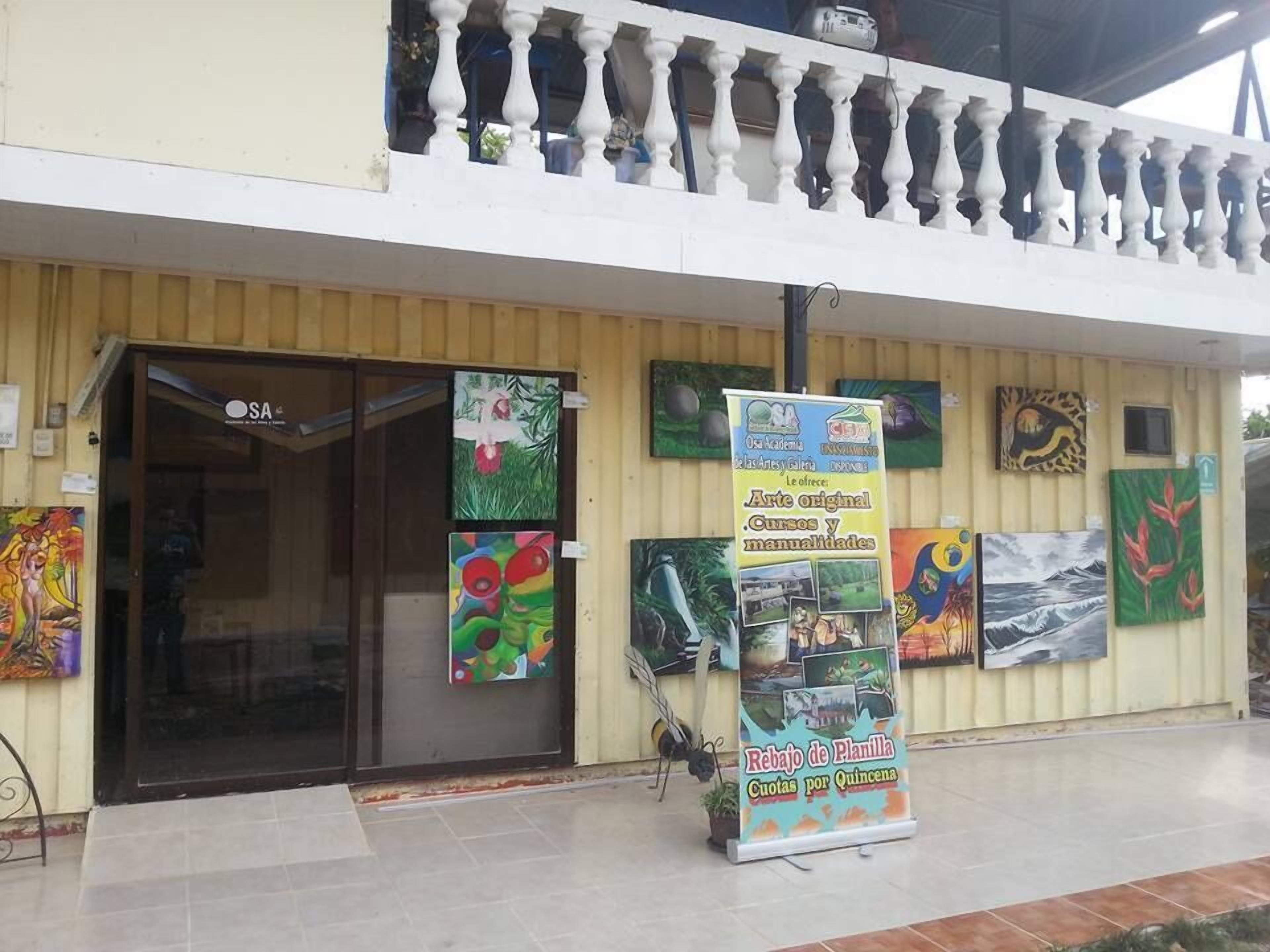 Um edifício com varanda, uma porta com letreiro e várias pinturas na parede.
