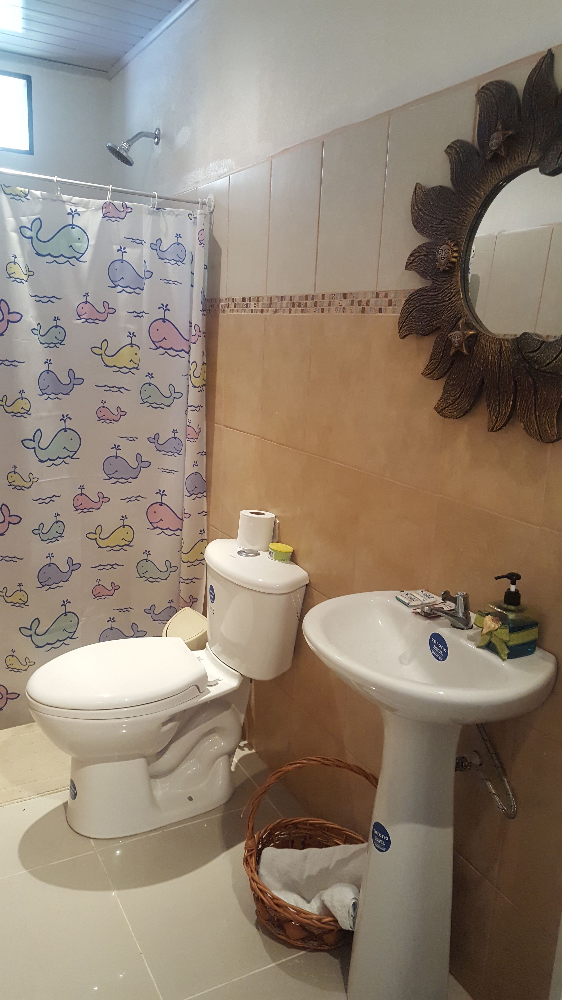 A bathroom with a toilet, sink, and shower curtain with whale patterns.