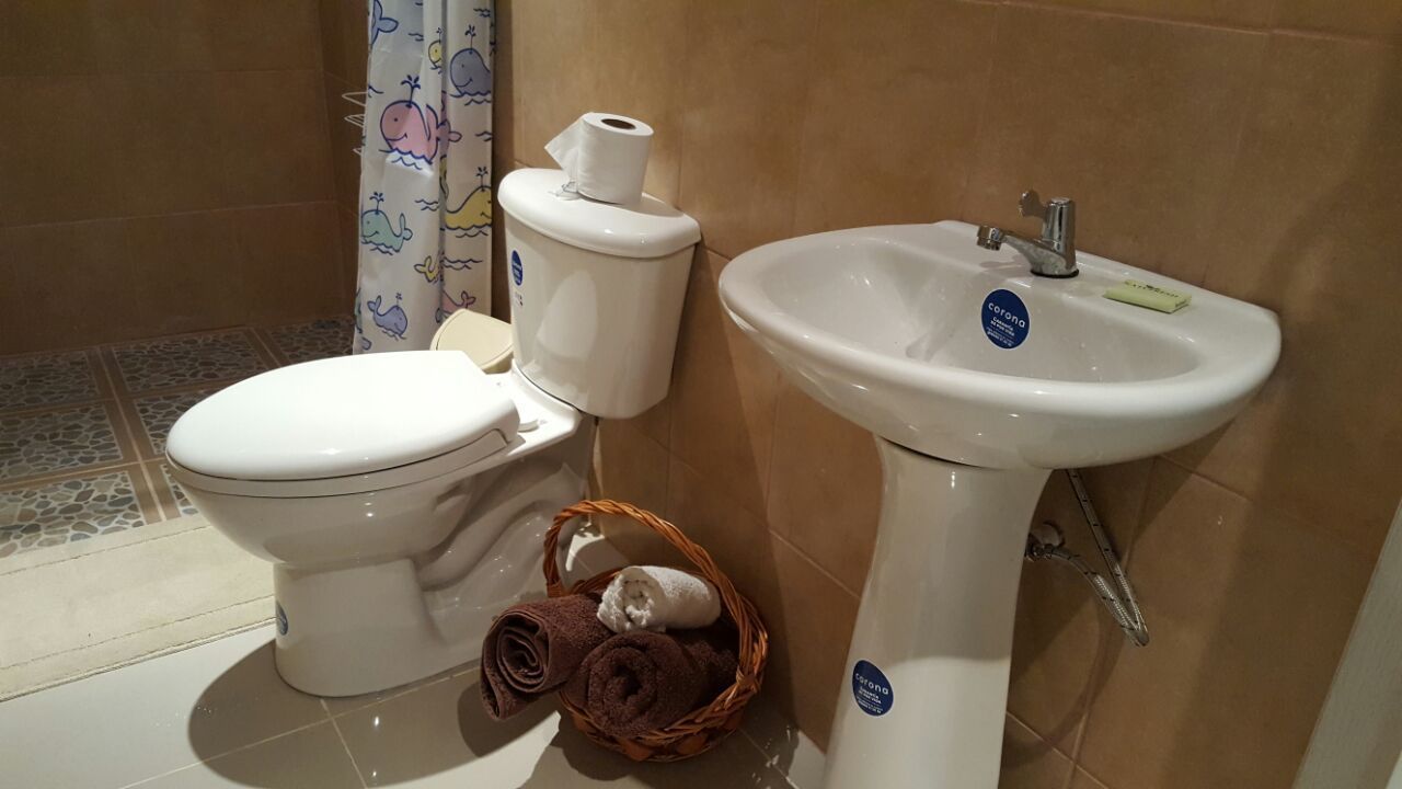 Een badkamer met toilet, wastafel en douchegordijn met walpatroon.