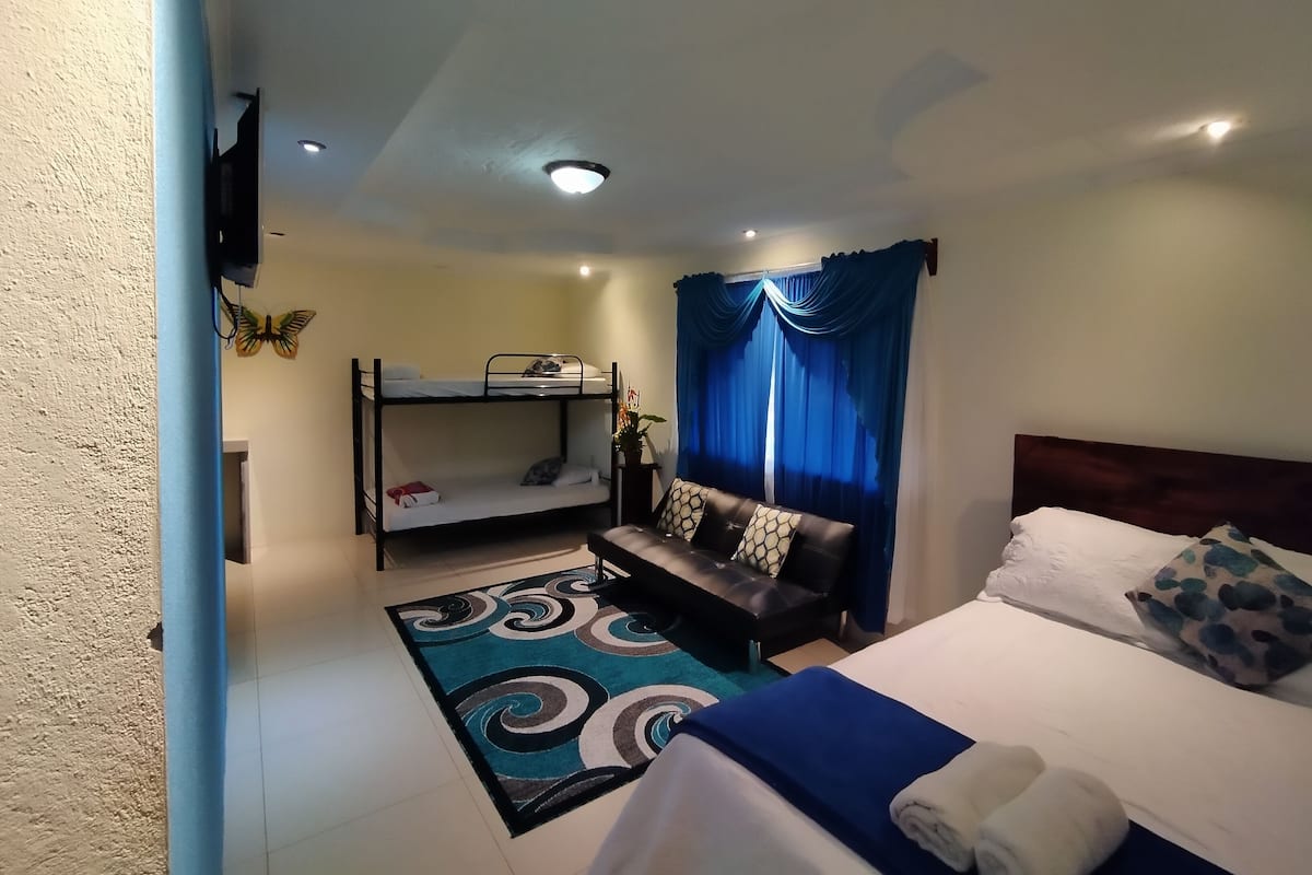 Une chambre avec des lits superposés, un canapé, un lit et un rideau bleu.