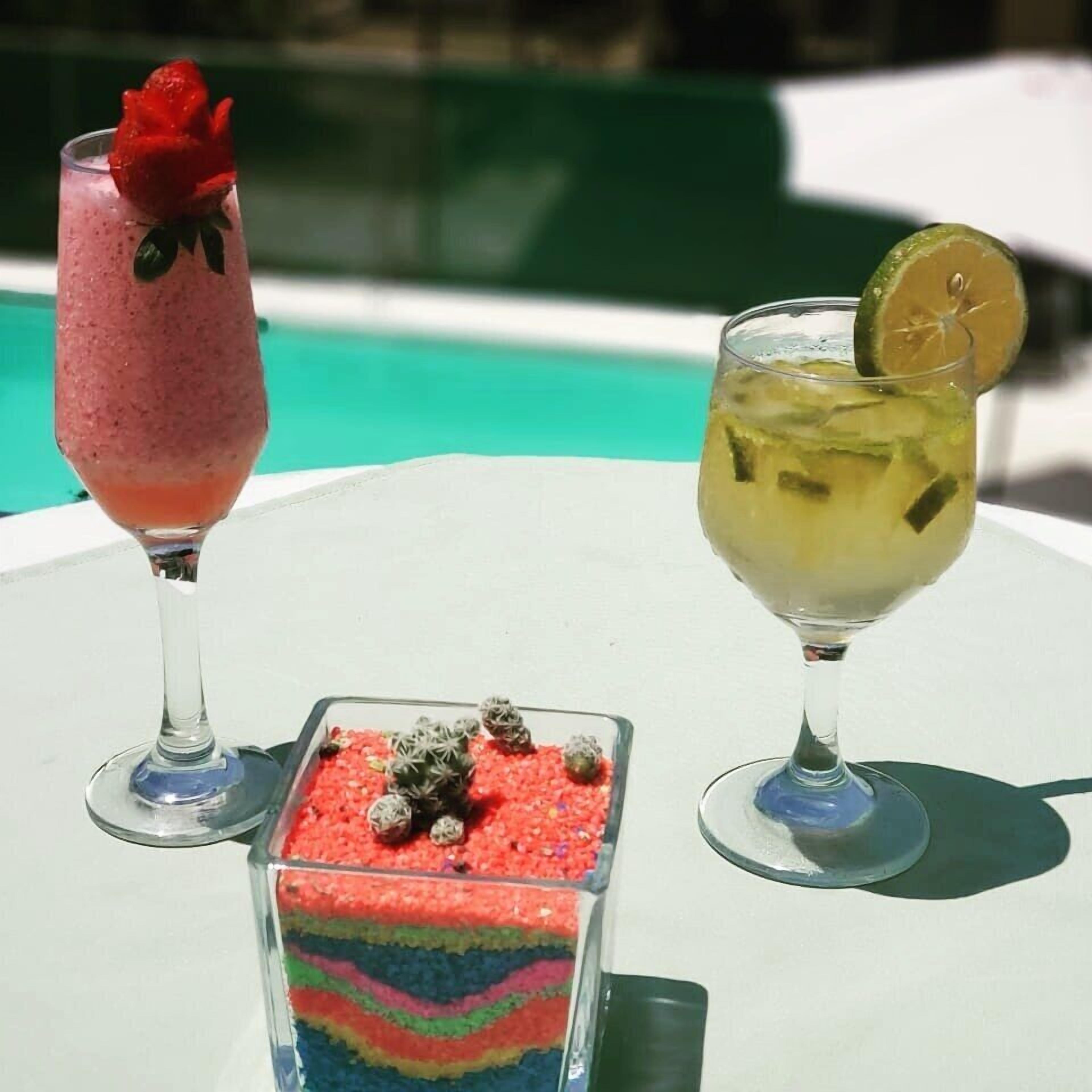 Deux boissons sur une table blanche, au bord d’une piscine.