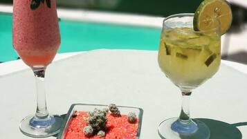 Deux boissons sur une table blanche, au bord d’une piscine.