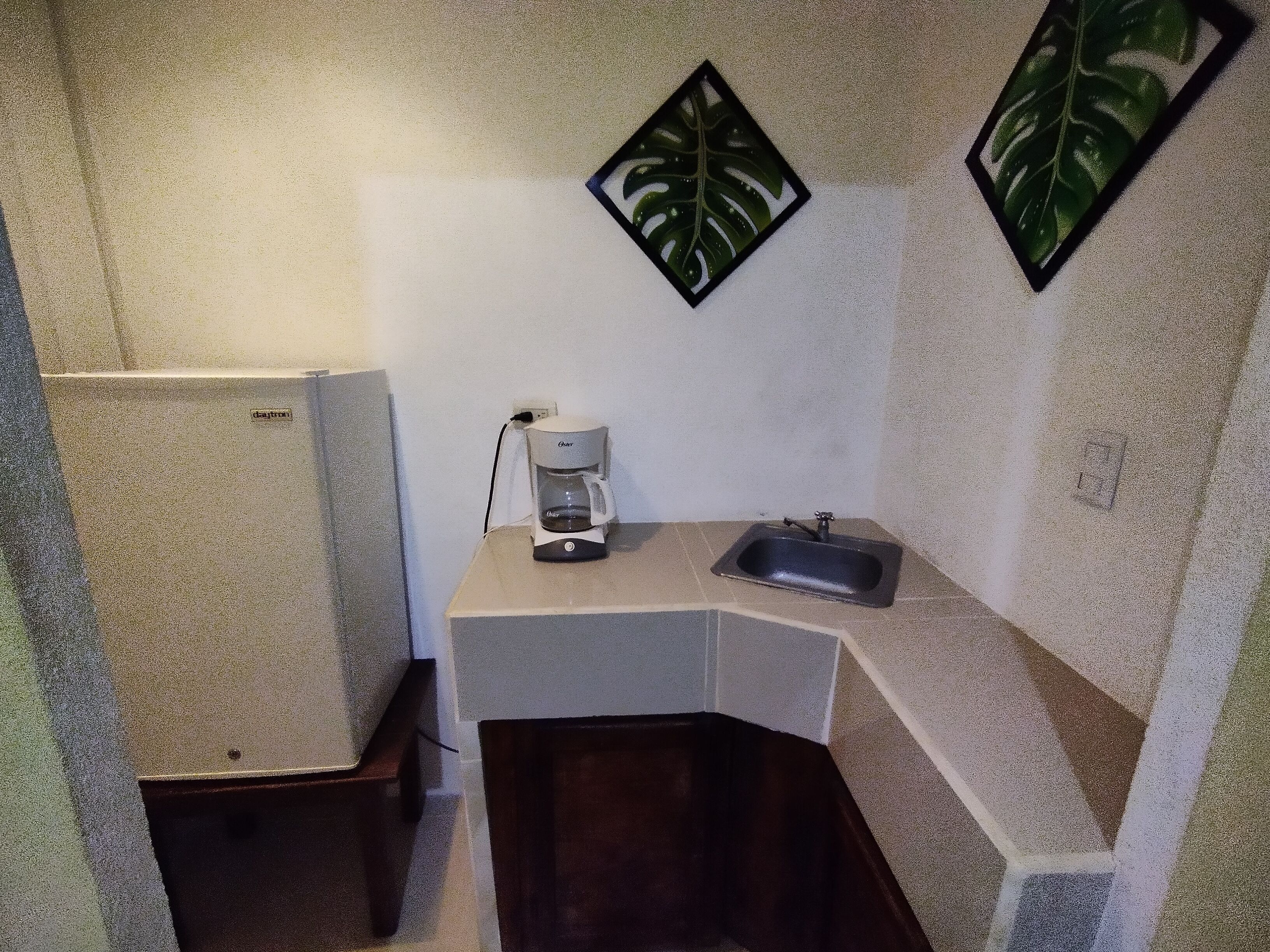 A small bathroom with a sink, a coffee maker, and a shower stall.
