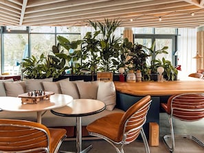 Un interior moderno con una mesa de madera, sillas de cuero, un sofá y diversas plantas.
