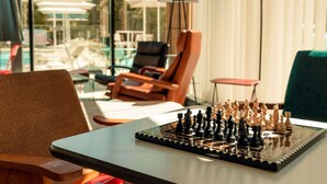 A chessboard on a table in a room with a view of outdoor seating and umbrellas. - ibis Budget La Rochelle Centre Gare (La Rochelle)