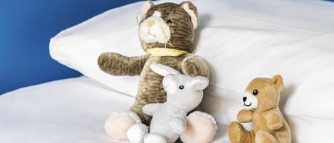 A bed with three stuffed animals: a brown bear, a white rabbit, and a brown bear.
