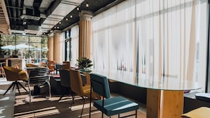 Um interior moderno com mesa de vidro, piso de madeira e uma combinação de cadeiras amarelas e verde-água.