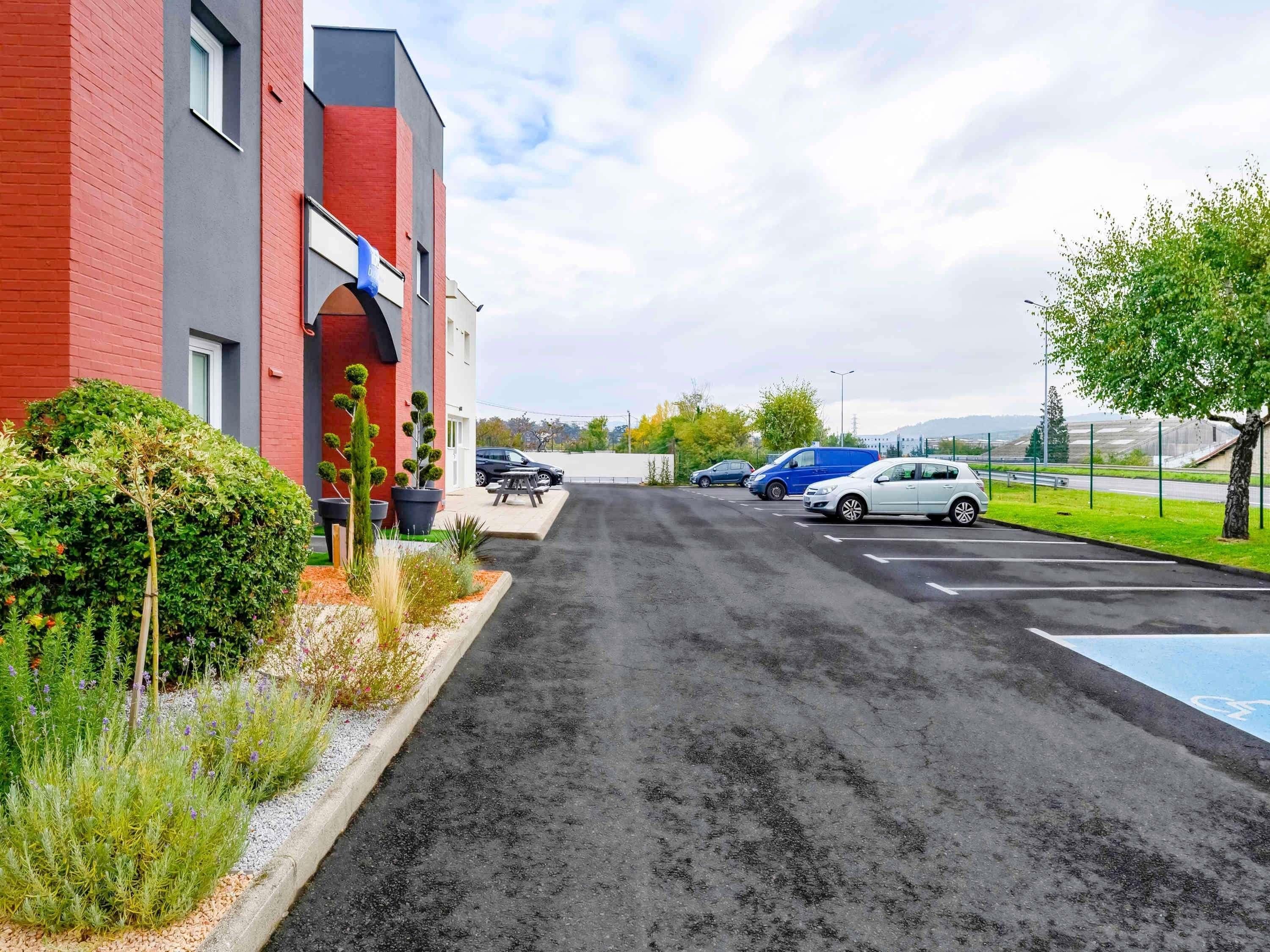 A parking area with a red building, a blue flag, and a clear sky.