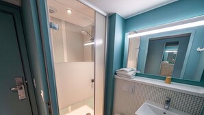 Een badkamer met een douchecabine van glas, een wit toilet, een wastafel met spiegel en een handdoekrek.