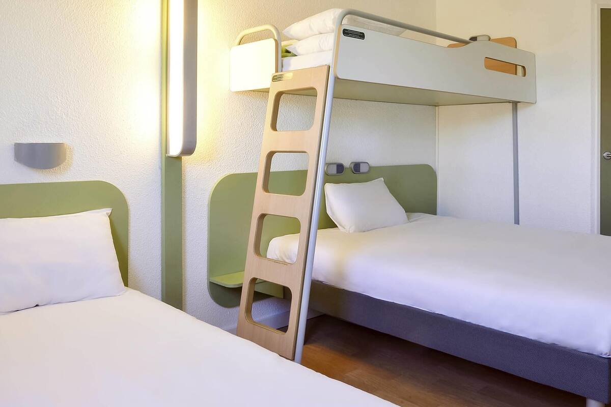 Dormitorio con literas, dos almohadas y una mesita de noche.
