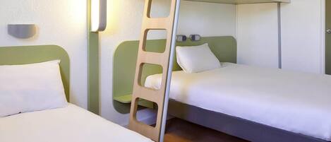 A bunk bed room with a ladder, two pillows, and a bedside table.