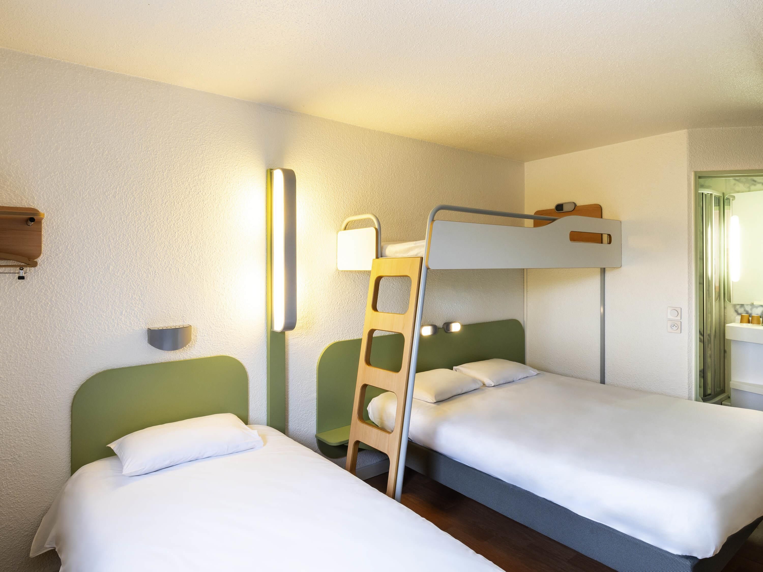 A bunk bed room with a ladder, a bedside table, and a wall-mounted light fixture.
