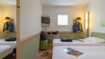 A hotel room with two beds, a desk with a computer, a mirror, and a window.
