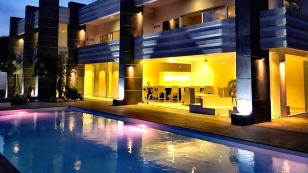 Un hotel moderno con piscina, que destaca por su estructura de varios niveles e iluminación interior cálida.