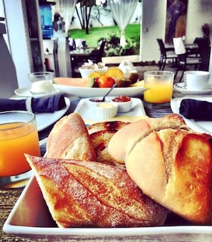 A breakfast tray with toast, a glass of orange juice, and a plate of fruit. - CASA-22 Luxury Boutique Hotel (Sosúa)