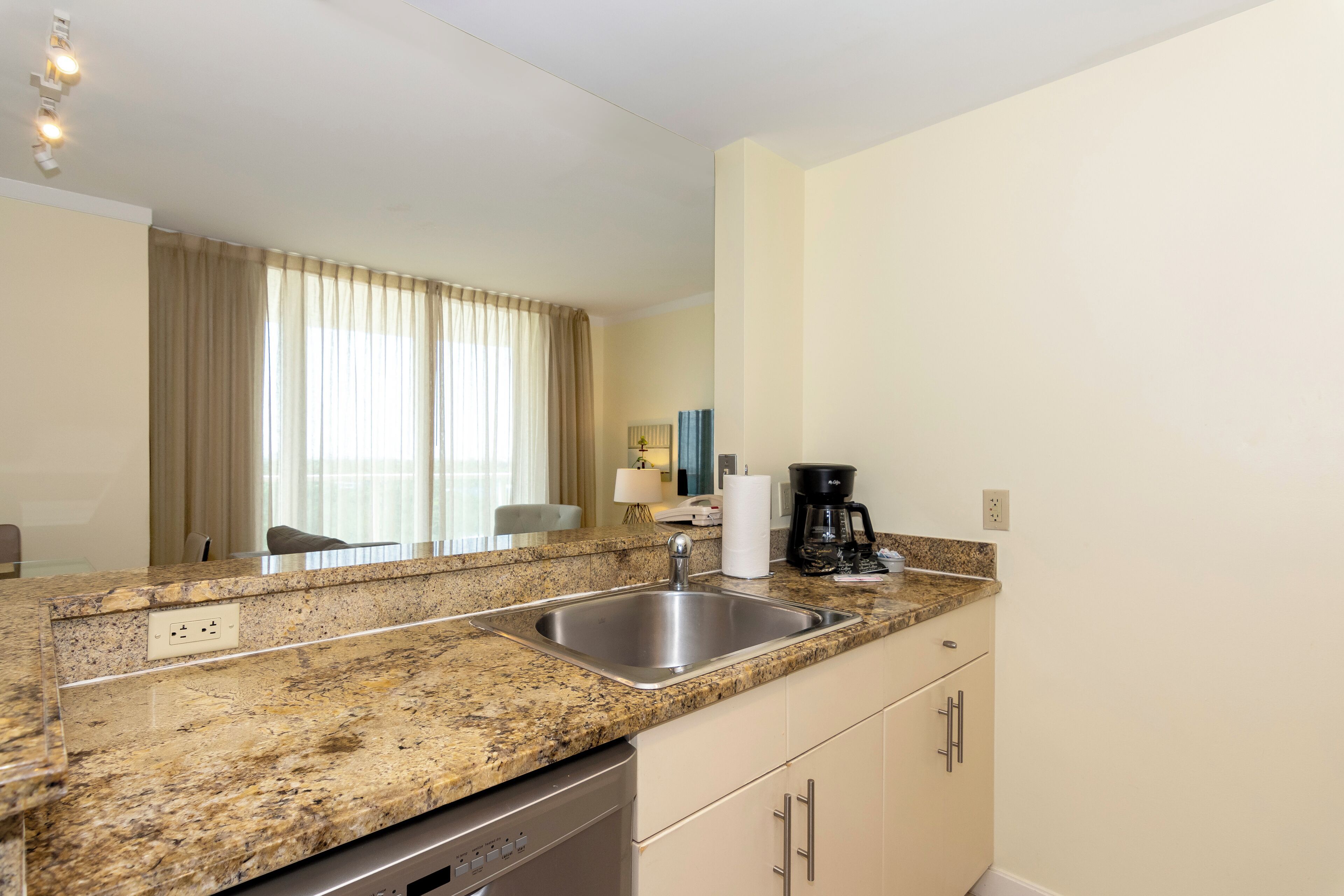 A modern kitchen with granite countertops, a stainless steel sink, and a dishwasher.