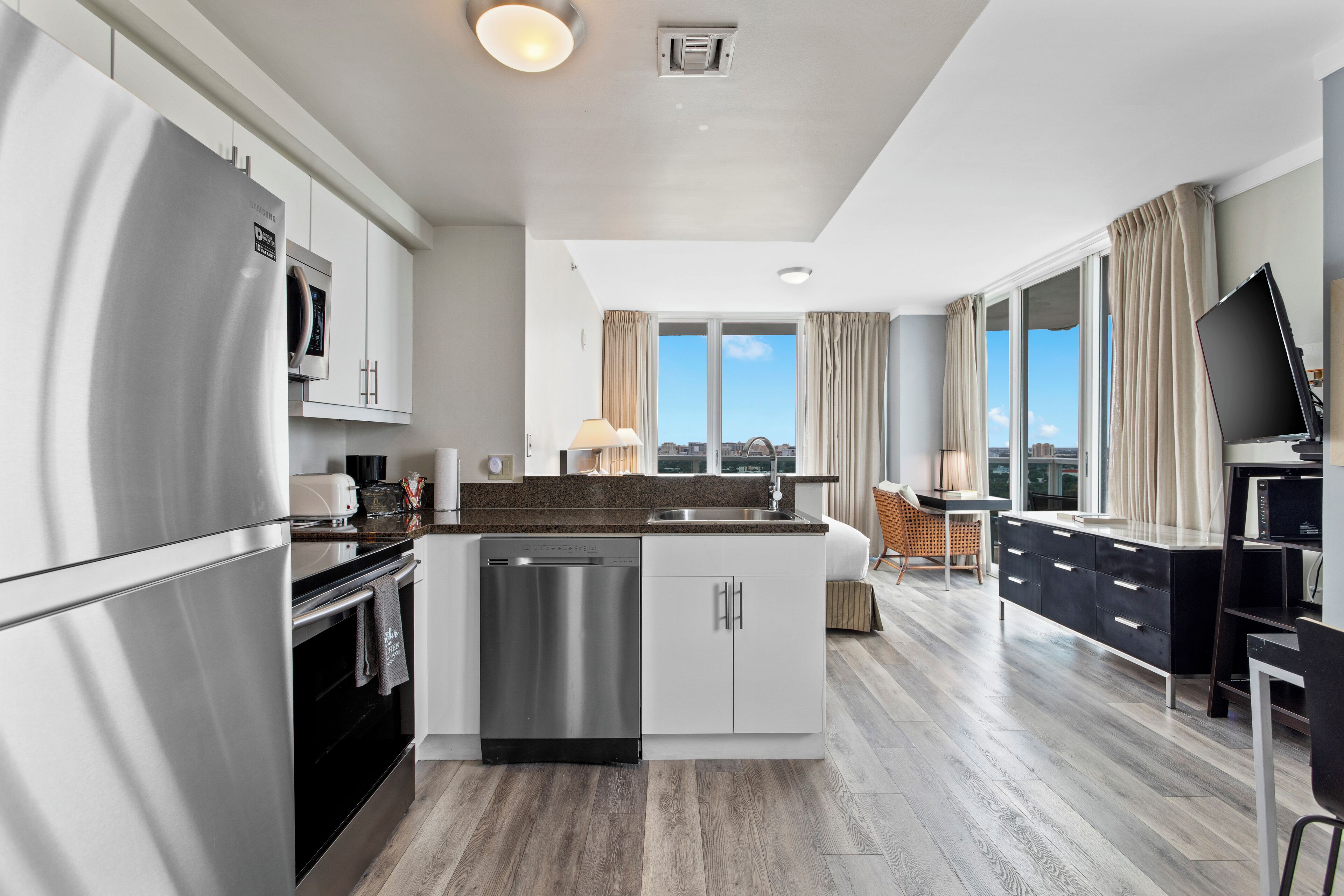 Una cocina moderna con electrodomésticos de acero inoxidable, una isla central y vistas de la ciudad a través de amplios ventanales.