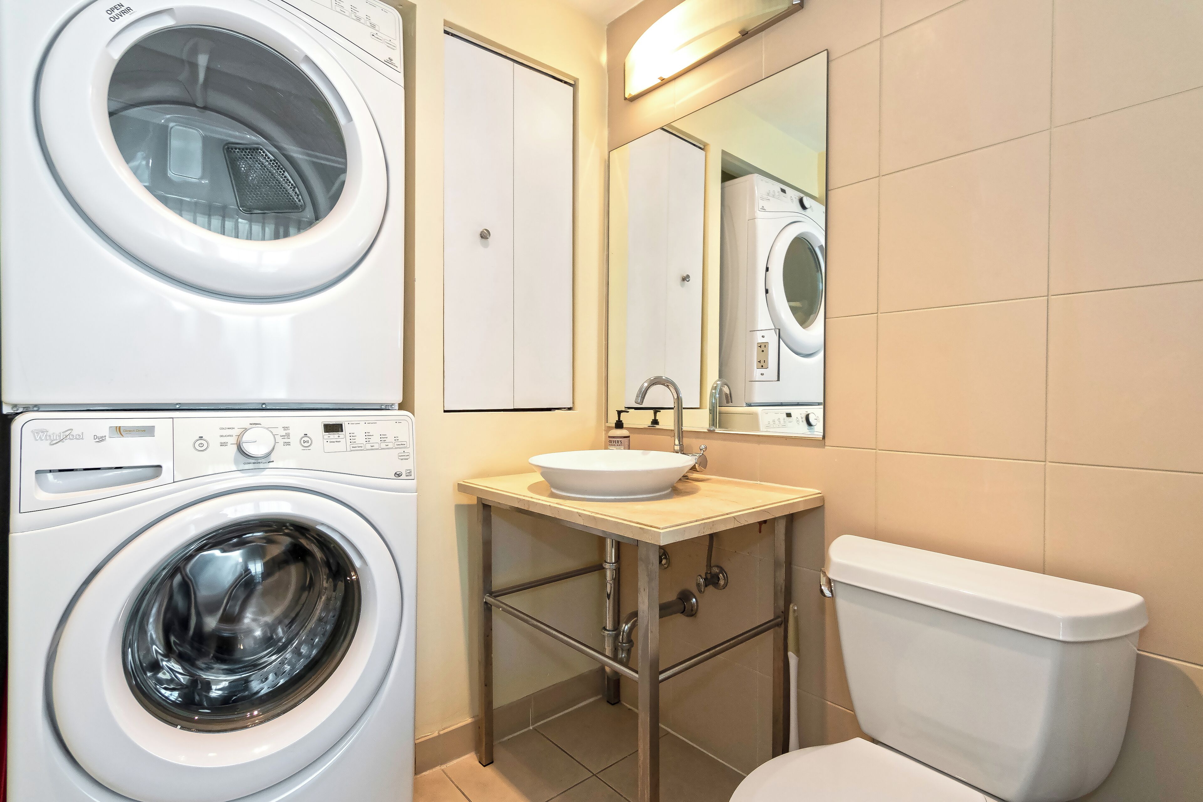 Un baño pequeño con lavadora, lavamanos e inodoro.