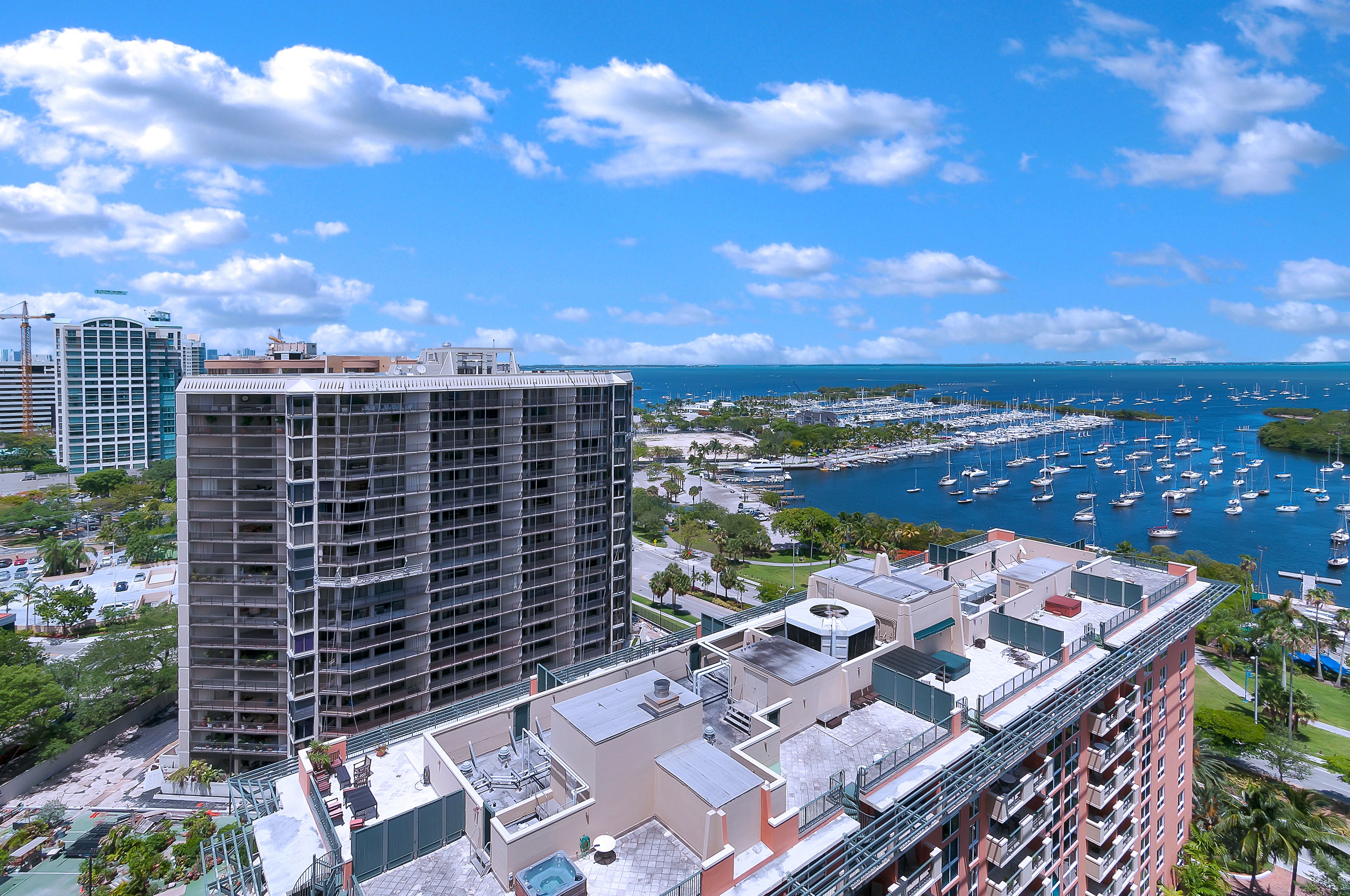 A high-rise building with multiple balconies overlooking a marina with numerous boats.