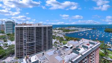 A high-rise building with multiple balconies overlooking a marina with numerous boats.