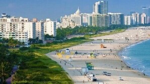 Un paisaje urbano costero con una playa, rascacielos y cielo despejado.
