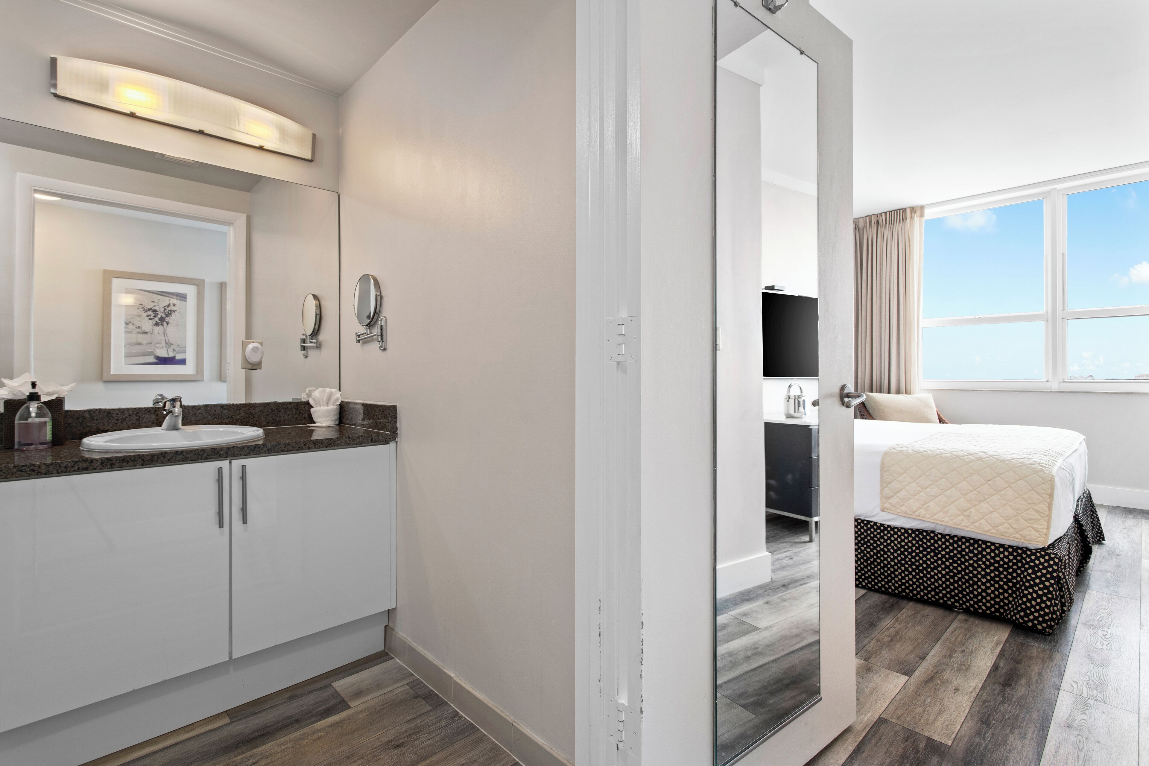 A modern hotel bathroom with a large sink, mirror, and a framed picture on the wall.