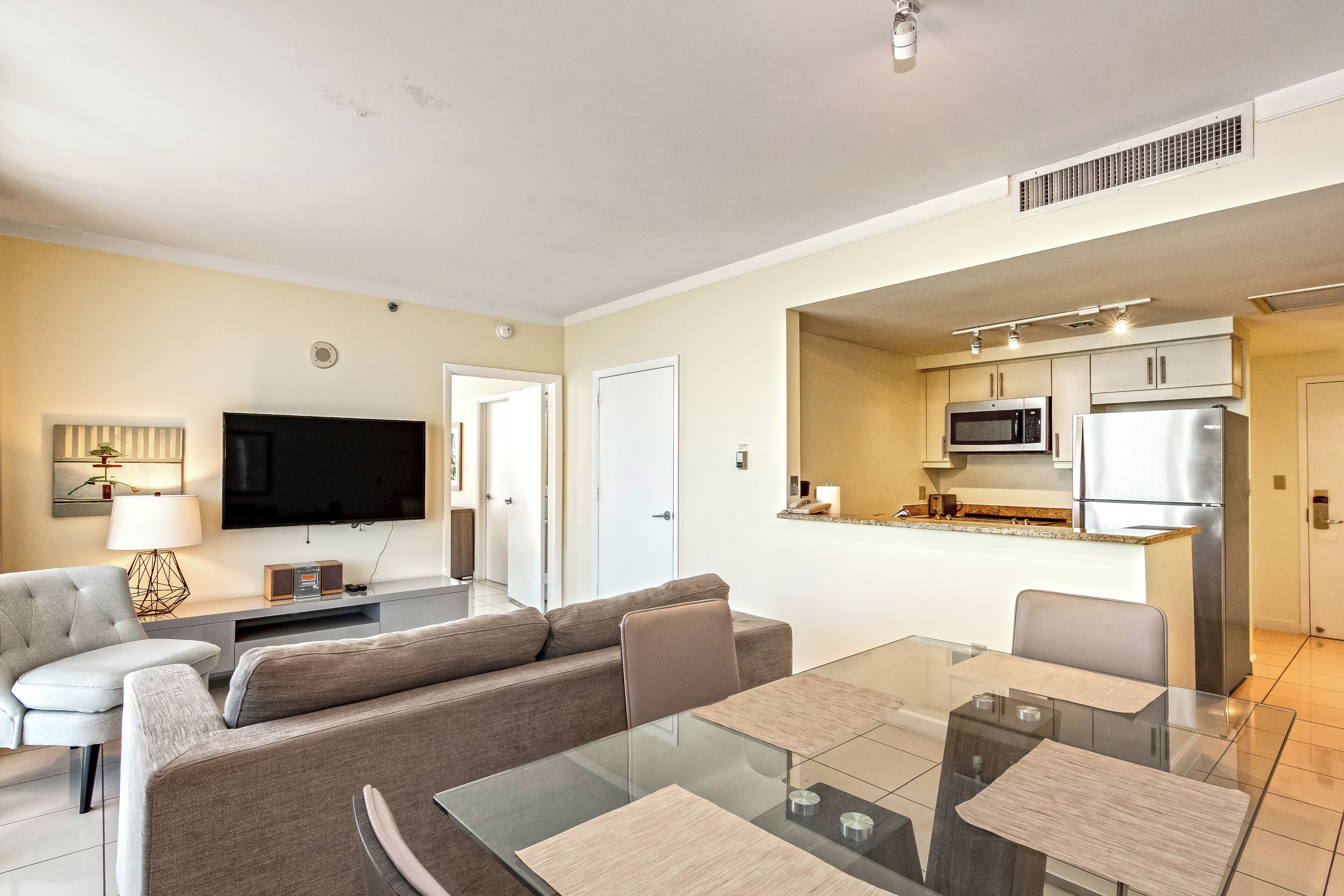 Una sala moderna con un sofá, televisor y una mesa de comedor de vidrio.