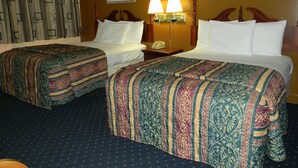 A hotel room with two beds, a nightstand with a lamp, and two framed pictures on the wall. - Fairfax Motel (Roanoke Rapids)